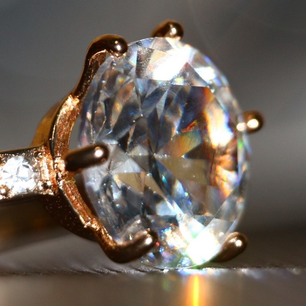 A
							close-up of prongs that are holding a diamond in
							place in a gold ring